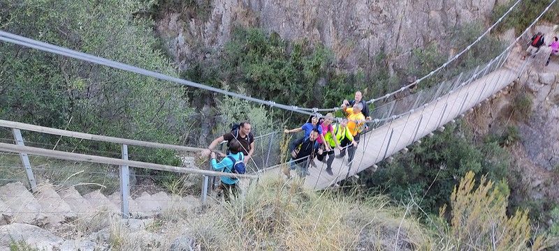 Grupo de senderismo cruzando uno de los puentes colgantes de Chulilla