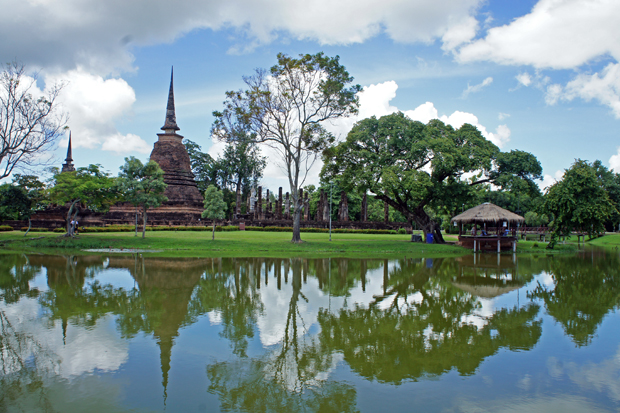 Estanque, árboles y monumentos en Sukhothai