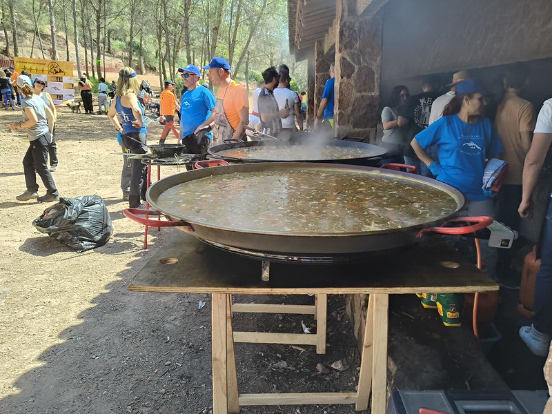 Comida preparada en grandes recipientes y participantes de una gastroruta