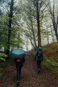 Dos senderistas caminan por un sendero boscoso bajo la lluvia